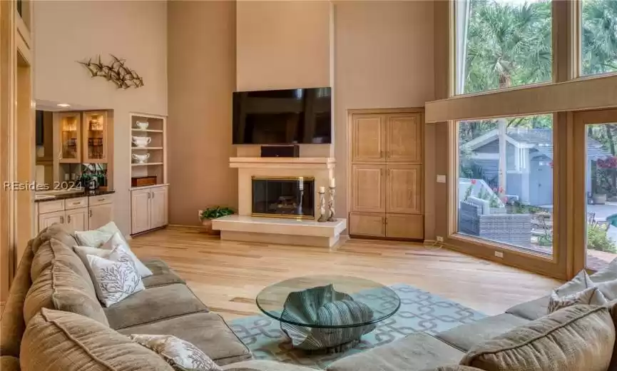 Living room featuring light hardwood / wood-style floors, built in shelves, and a high ceiling