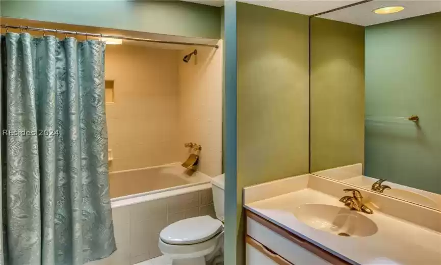 Full bathroom with toilet, a textured ceiling, vanity, and shower / bathtub combination with curtain