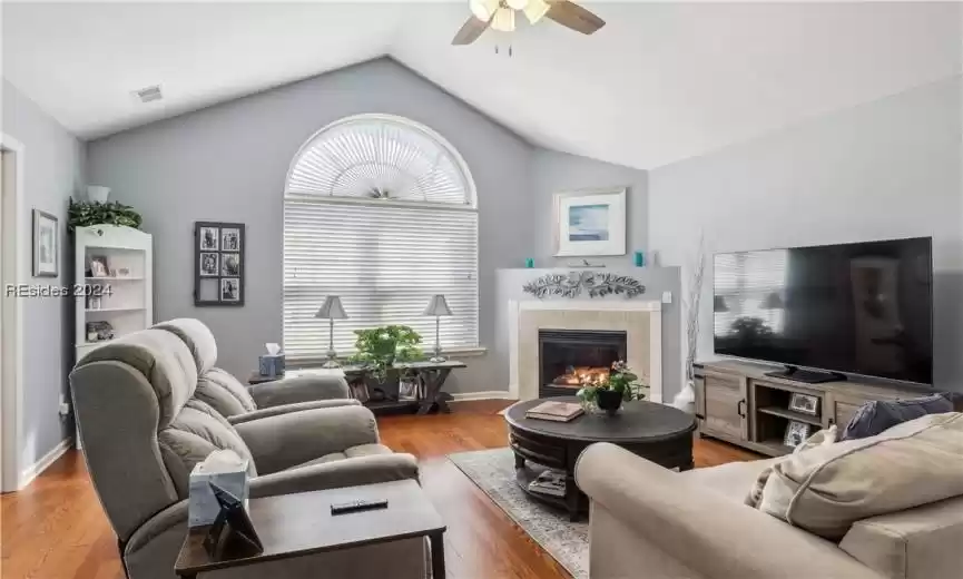 Living room with light hardwood / wood-style flooring, ceiling fan, vaulted ceiling, and a healthy amount of sunlight