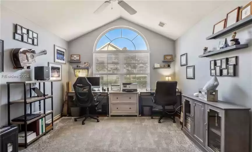 Carpeted home office with lofted ceiling and ceiling fan