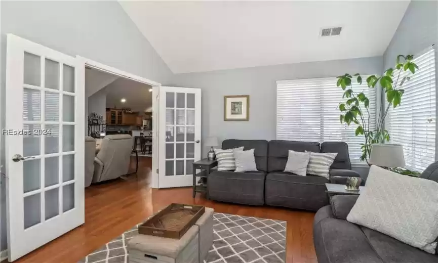 Living room with hardwood / wood-style flooring, high vaulted ceiling, and french doors