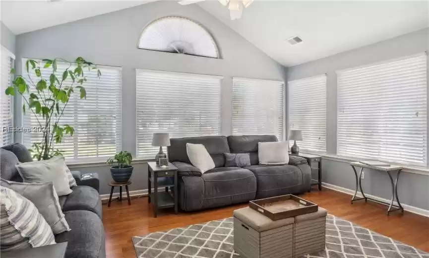 Living room with dark hardwood / wood-style flooring, high vaulted ceiling, and ceiling fan