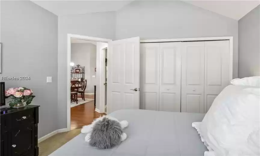 Bedroom featuring lofted ceiling, light carpet, and a closet