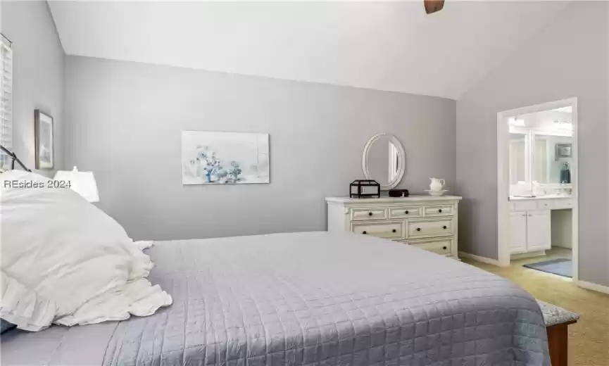 Carpeted bedroom featuring high vaulted ceiling, ceiling fan, and ensuite bathroom