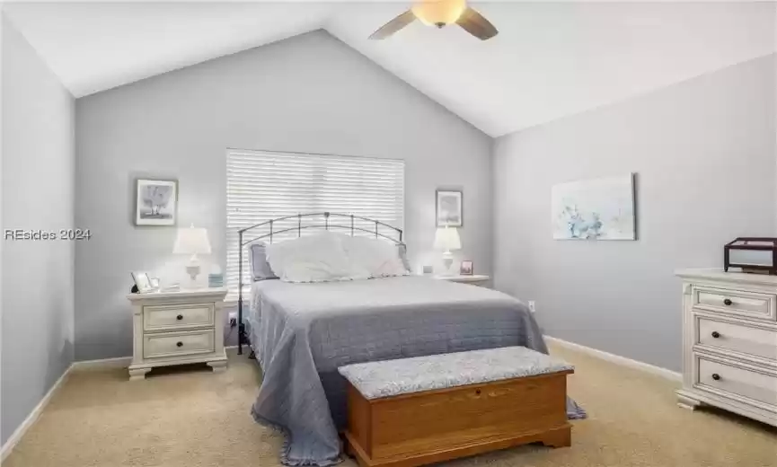 Bedroom featuring ceiling fan, light colored carpet, and lofted ceiling