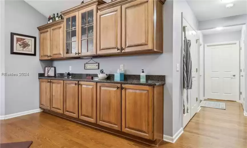 Kitchen with light hardwood / wood-style flooring and dark stone countertops