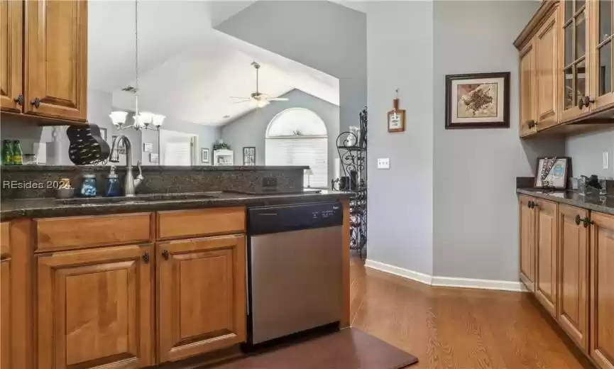 Kitchen featuring lofted ceiling, ceiling fan with notable chandelier, dark hardwood / wood-style floors, sink, and stainless steel dishwasher