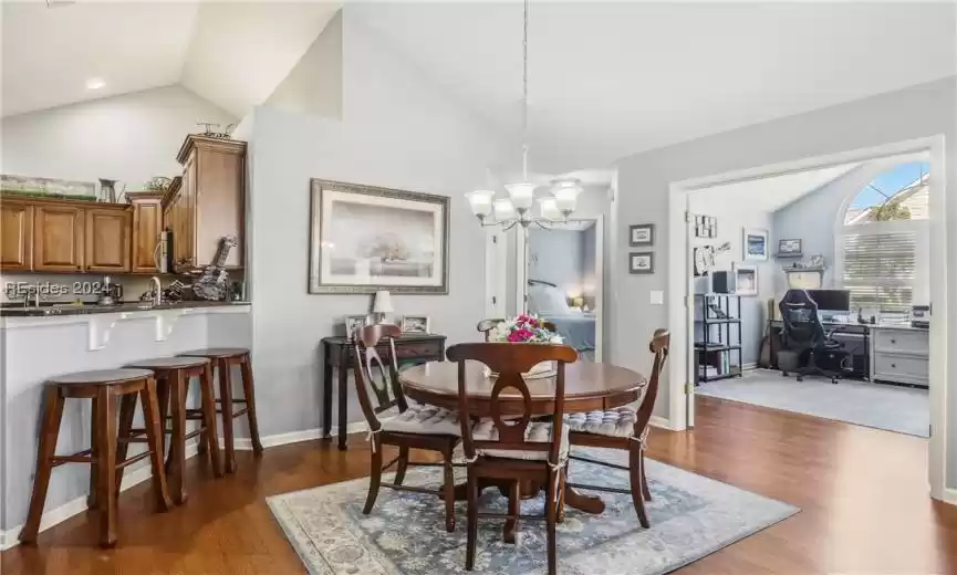 Dining room featuring an inviting chandelier, dark hardwood / wood-style floors, and vaulted ceiling