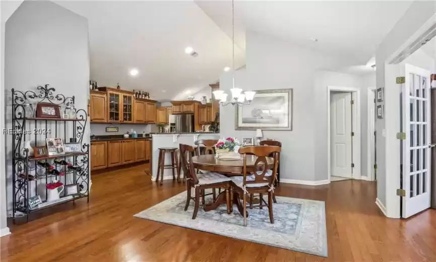 Dining area featuring dark wood-type flooring, an inviting chandelier, and high vaulted ceiling