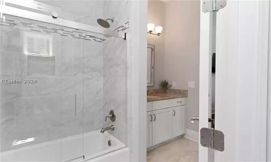 Bathroom featuring tile floors, vanity, and tiled shower / bath