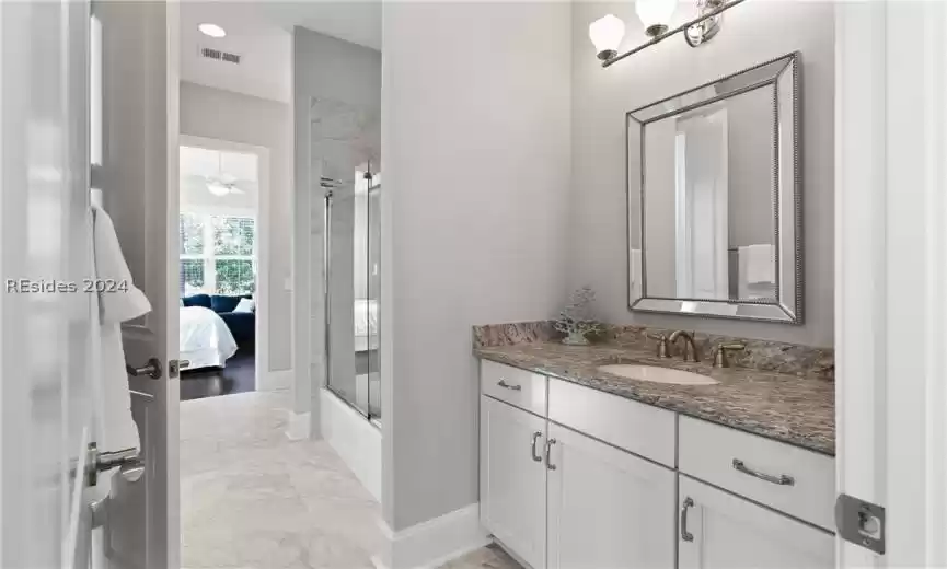 Bathroom with bath / shower combo with glass door, vanity, ceiling fan, and tile flooring