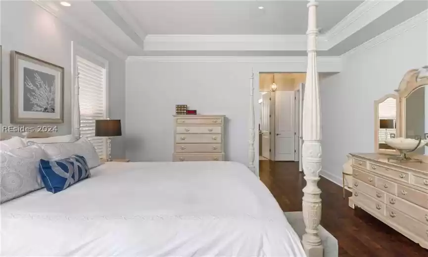 Bedroom featuring a raised ceiling, dark hardwood / wood-style floors, crown molding, and ceiling fan