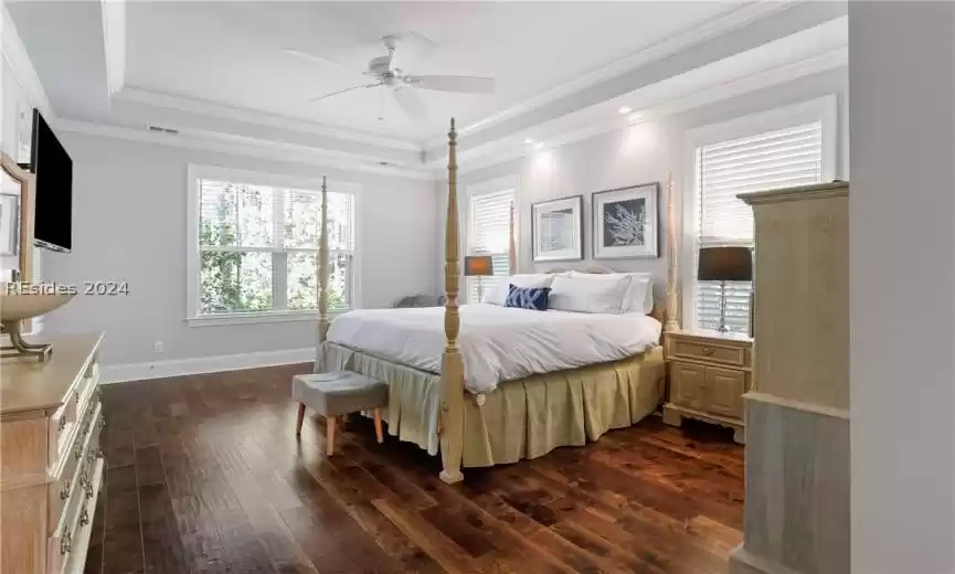 Bedroom with ceiling fan, dark wood-type flooring, a raised ceiling, and ornamental molding