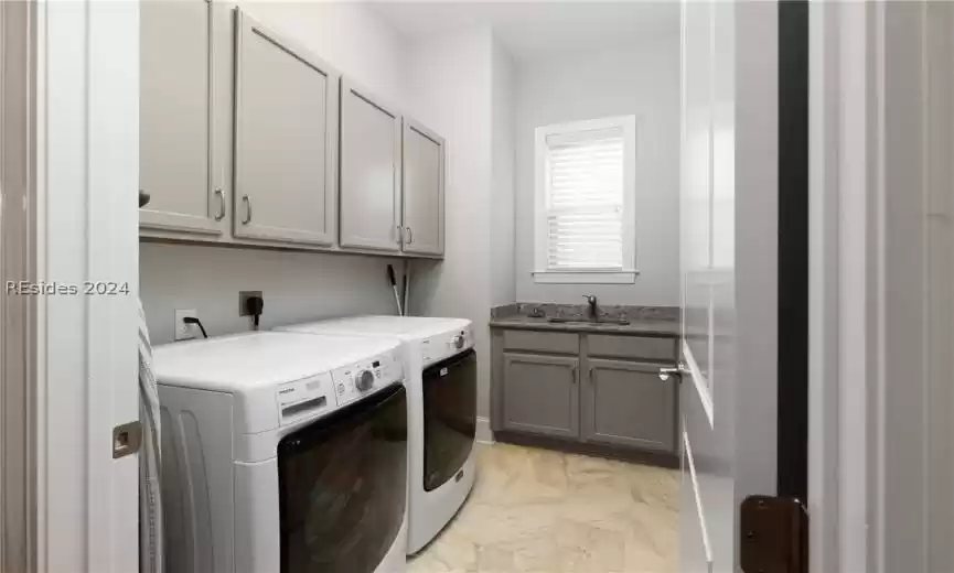 Clothes washing area featuring cabinets, hookup for an electric dryer, sink, and washer and clothes dryer