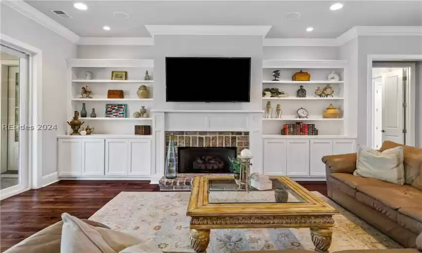 Living room with crown molding, dark hardwood / wood-style floors, and a fireplace
