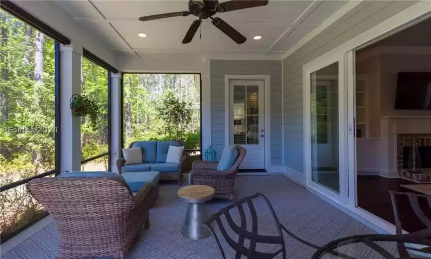 Sunroom / solarium featuring ceiling fan and a brick fireplace