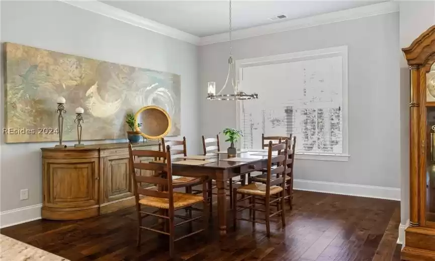 Dining room with a notable chandelier, dark hardwood / wood-style flooring, and ornamental molding