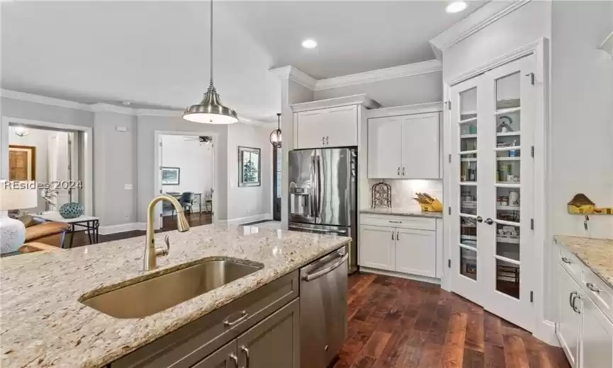 Kitchen featuring white cabinets, stainless steel appliances, decorative light fixtures, and sink
