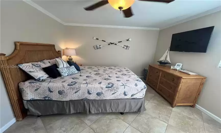 Tiled bedroom with ceiling fan and ornamental molding