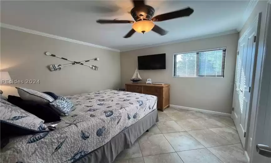 Tiled bedroom with crown molding and ceiling fan