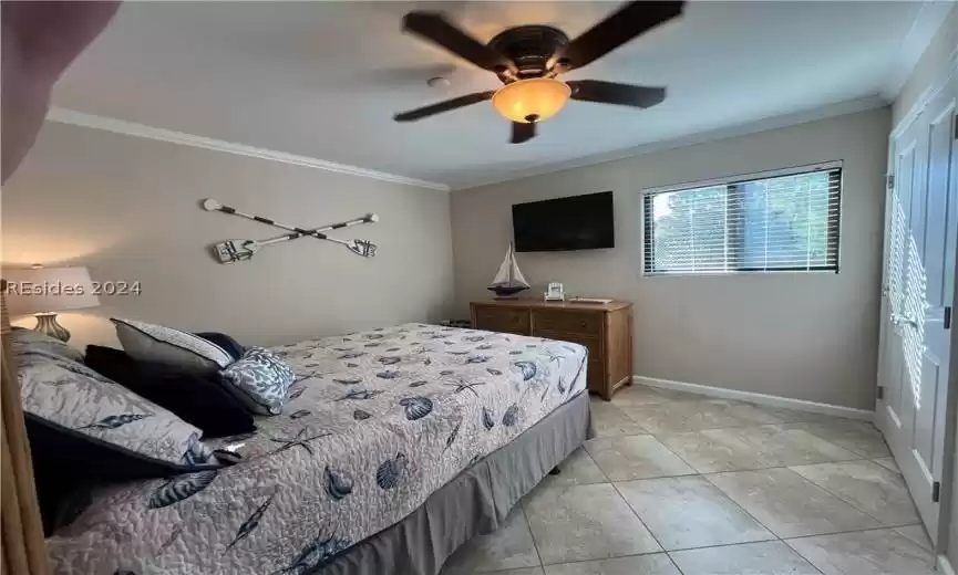 Tiled bedroom with ornamental molding and ceiling fan