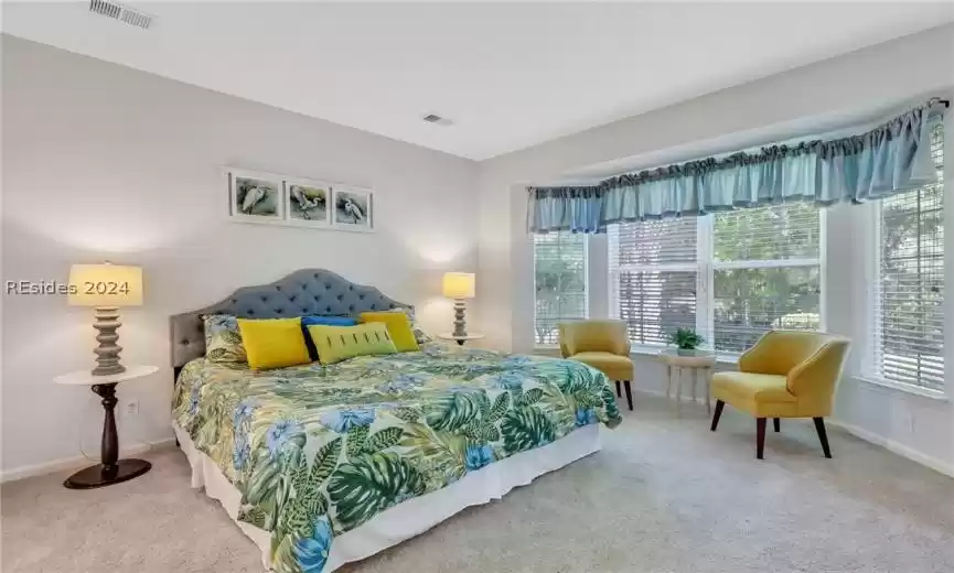 Freshly painted and carpeted bedroom featuring a bay window overlooking wooded backyard