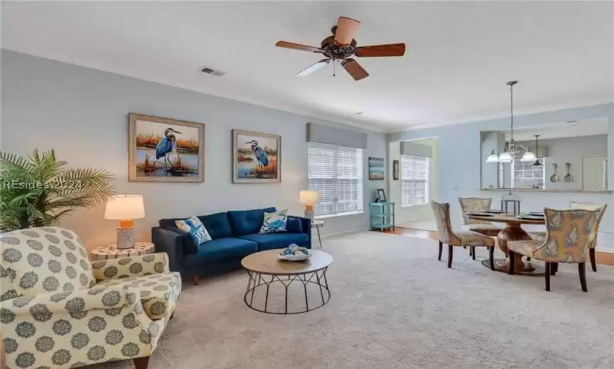 Great Room with new light carpet, a textured ceiling, crown molding, and ceiling fan with notable chandelier