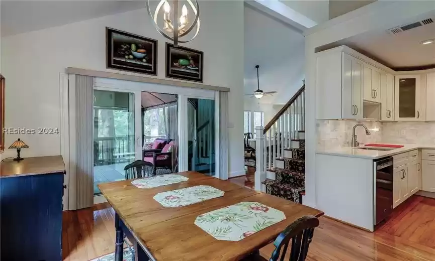 Dining area featuring ceiling fan with notable chandelier, sink, a healthy amount of sunlight, and hardwood / wood-style flooring