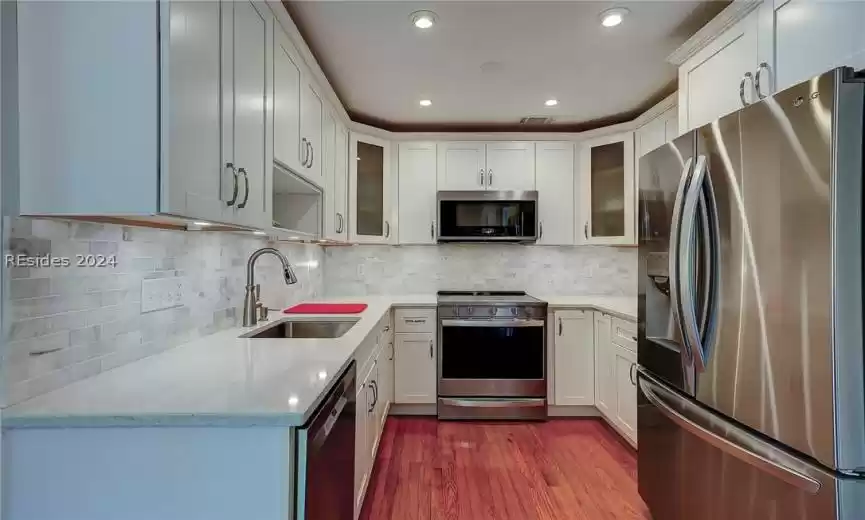 Kitchen featuring dark hardwood / wood-style flooring, backsplash, sink, and stainless steel appliances