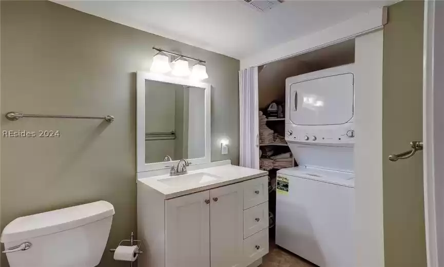 Bathroom featuring tile floors, toilet, vanity, and stacked washer and dryer