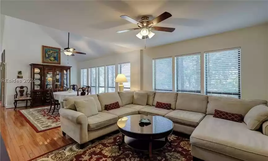 Living room featuring ceiling fan, hardwood / wood-style floors, and lofted ceiling