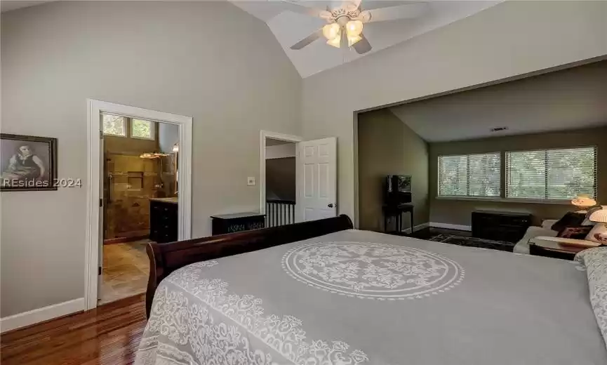 Bedroom featuring ceiling fan, high vaulted ceiling, dark hardwood / wood-style floors, and ensuite bath