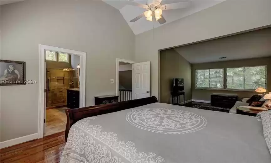 Bedroom featuring ceiling fan, connected bathroom, dark hardwood / wood-style floors, and high vaulted ceiling