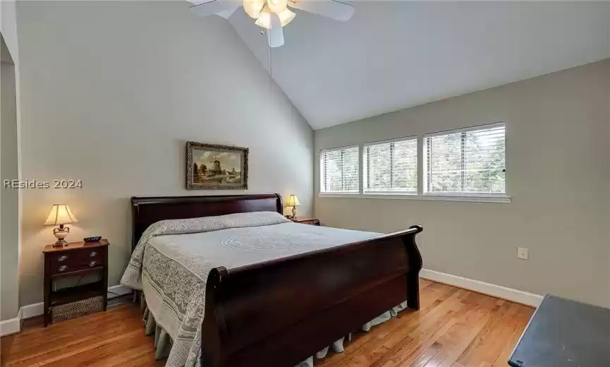 Bedroom with high vaulted ceiling, ceiling fan, and light hardwood / wood-style flooring