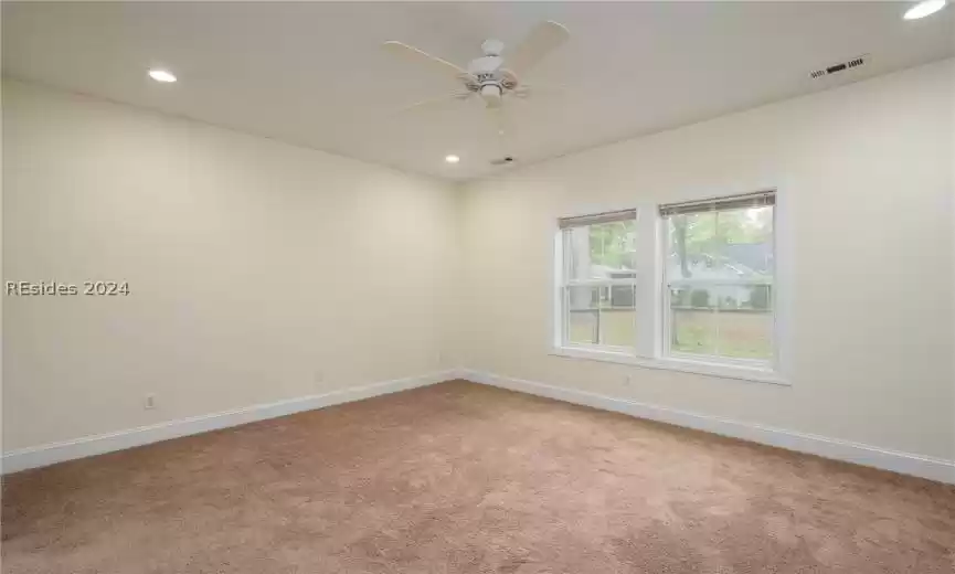 Empty room with ceiling fan and light colored carpet