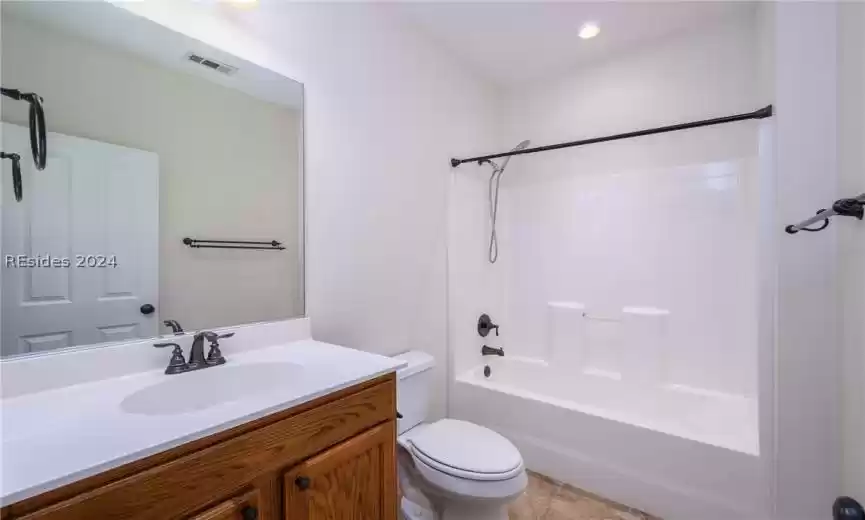 Full bathroom with tile floors, toilet, vanity, and tub / shower combination