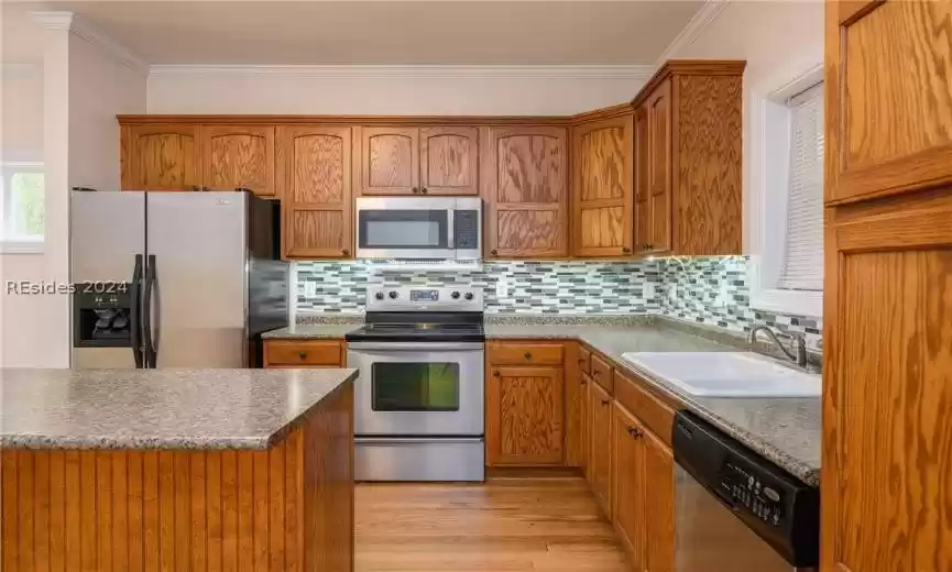 Kitchen featuring light wood-type flooring, tasteful backsplash, appliances with stainless steel finishes, and sink