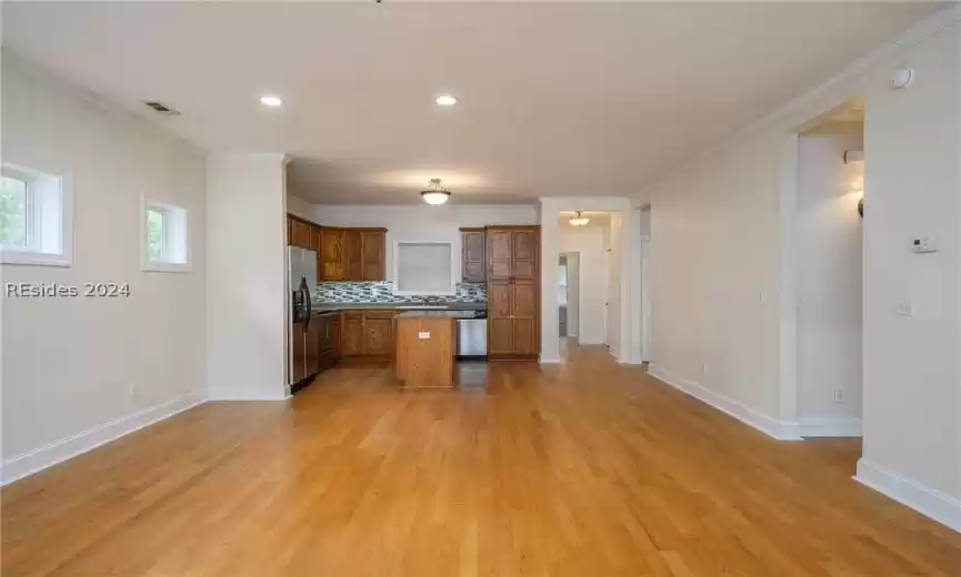 Kitchen with a kitchen island, tasteful backsplash, ornamental molding, and light hardwood / wood-style flooring