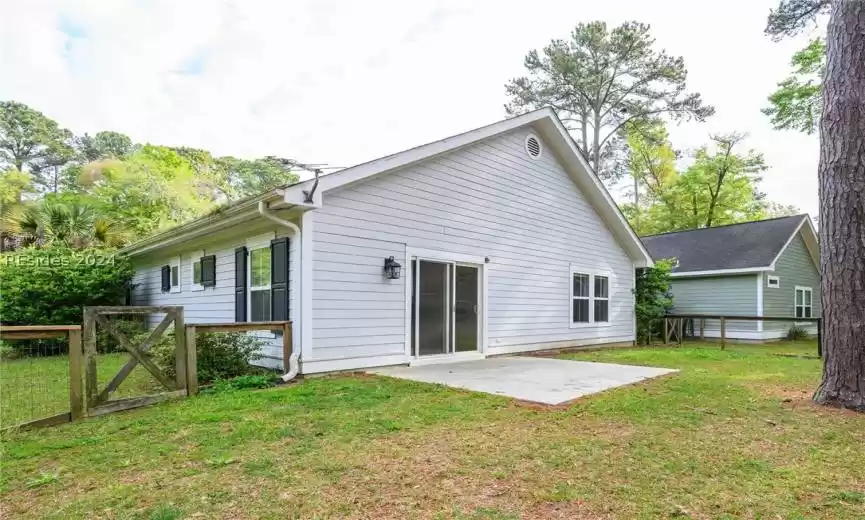 Back of house with a lawn and a patio