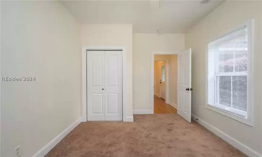 Unfurnished bedroom with light colored carpet and a closet