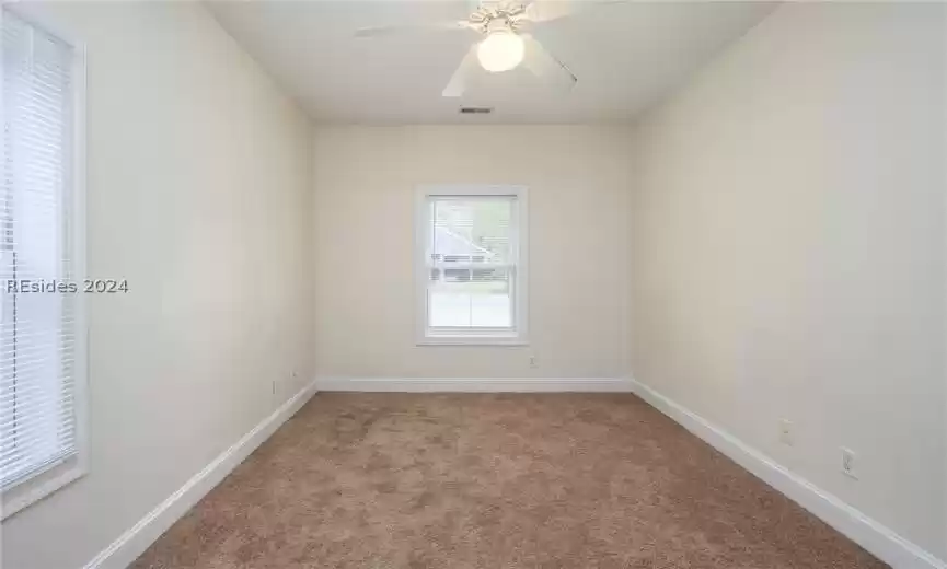 Carpeted empty room featuring ceiling fan