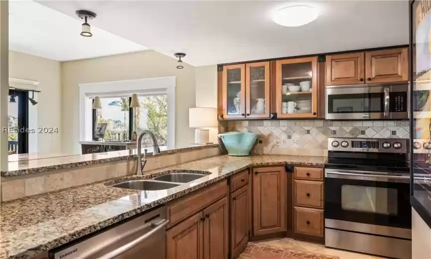 Granite countertops, stone backsplash, and deep Kohler kitchen sink.