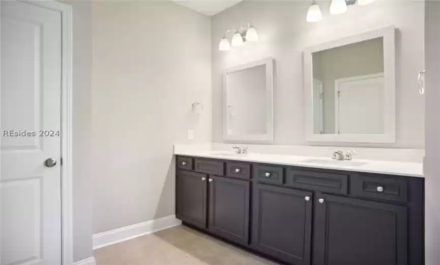 Bathroom with large vanity, tile floors, and double sink