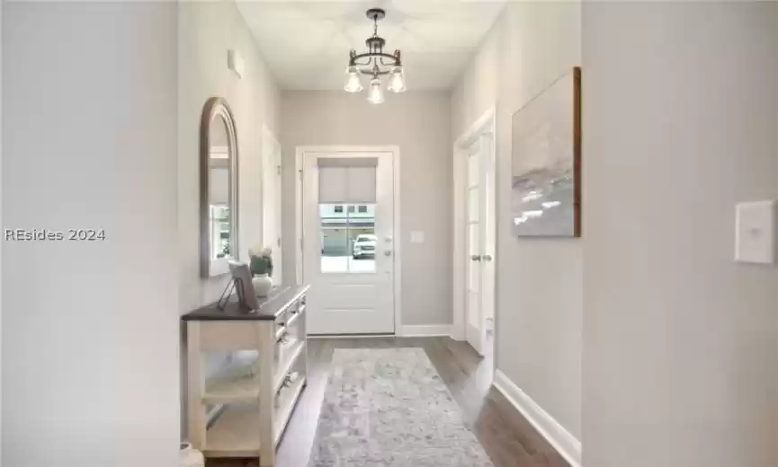 Doorway to outside with dark hardwood / wood-style floors and an inviting chandelier