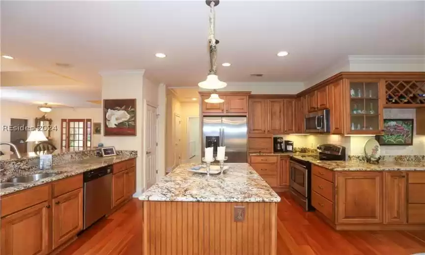 Kitchen featuring appliances with stainless steel finishes, sink, a center island, backsplash, and hanging pendant light fixtures