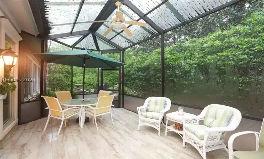 Screened, covered porch featuring vaulted ceiling, ceiling fans and door to the paver patio