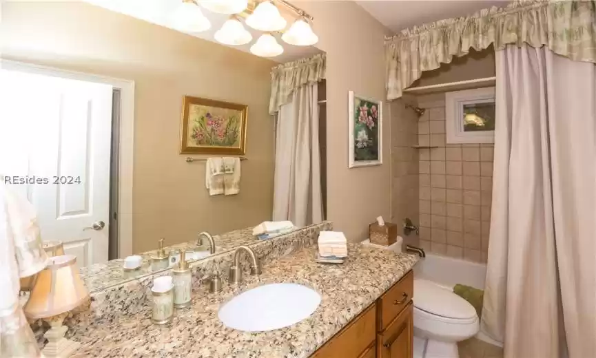 Full bathroom/powder room featuring comfort-height toilet, shower/tub combo, granite counter comfort-height vanity
