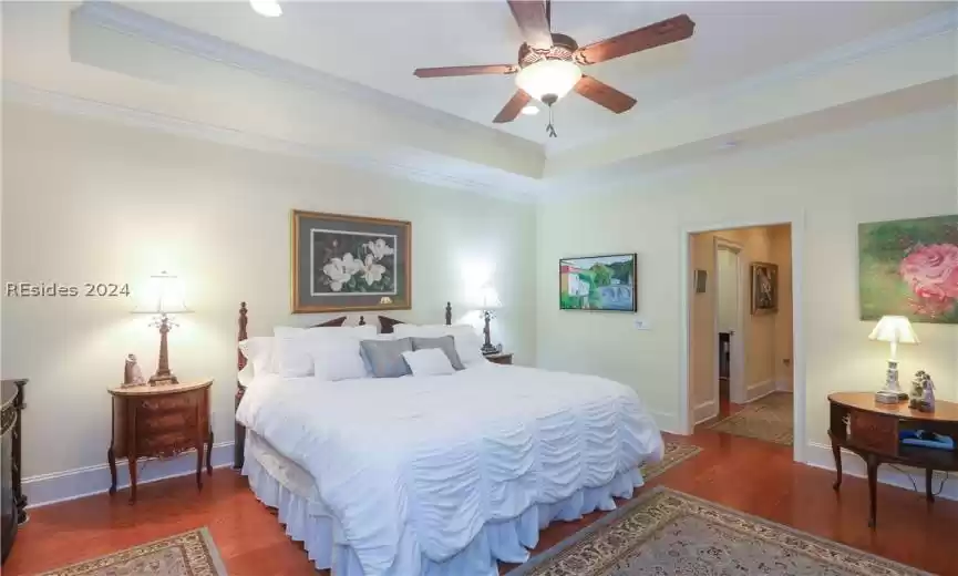 Bedroom featuring a raised ceiling, ornamental molding, and dark hardwood / wood-style flooring