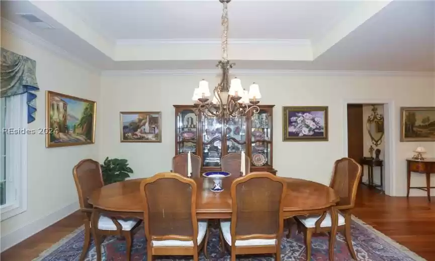 Dining space featuring a tray ceiling, dark hardwood / wood-style floors, an inviting chandelier, and crown molding