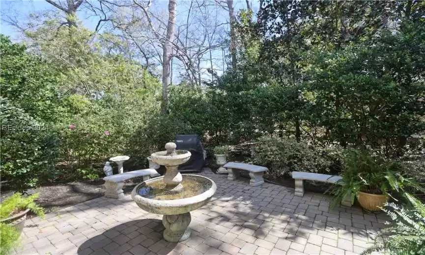 View of paver patio which has low voltage lighting and fountain on a timer.